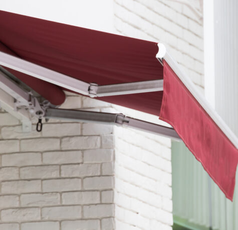 Red retractable awning near brick house